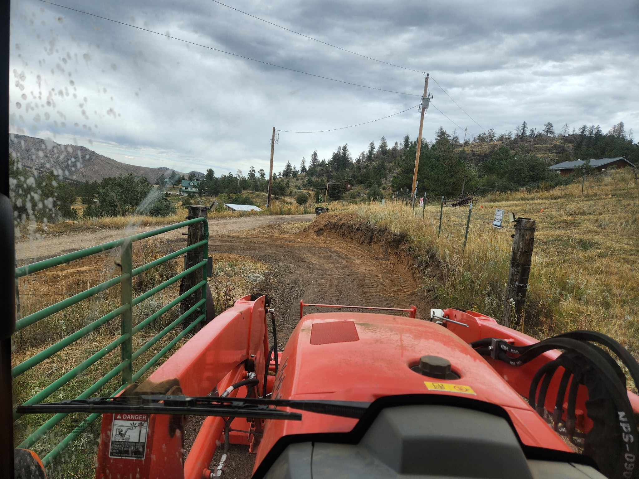 Recycled asphalt driveway — view from tractor near a gate with Colorado mountains in the background